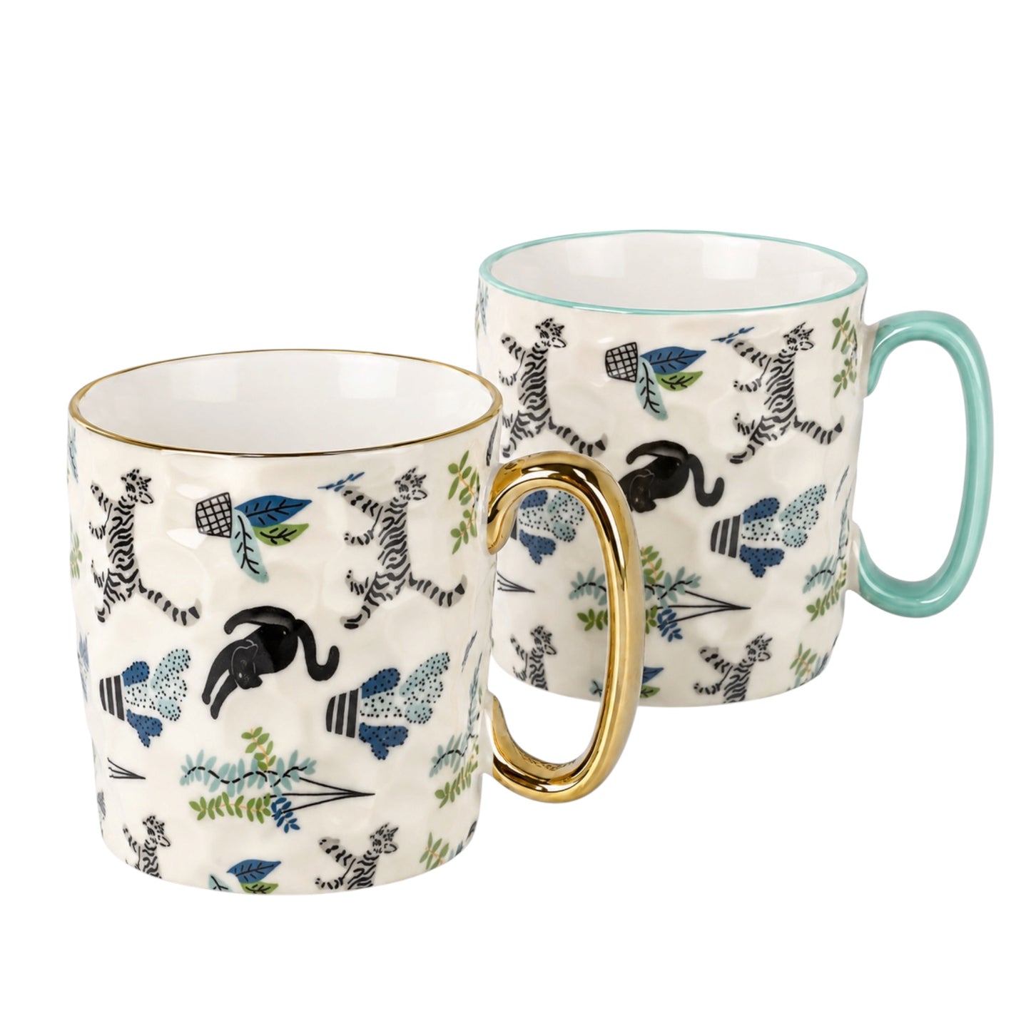 Two ceramic mugs with a white base, decorated with black and blue wild animals and botanical patterns, with one featuring a gold handle and the other a mint green handle.
