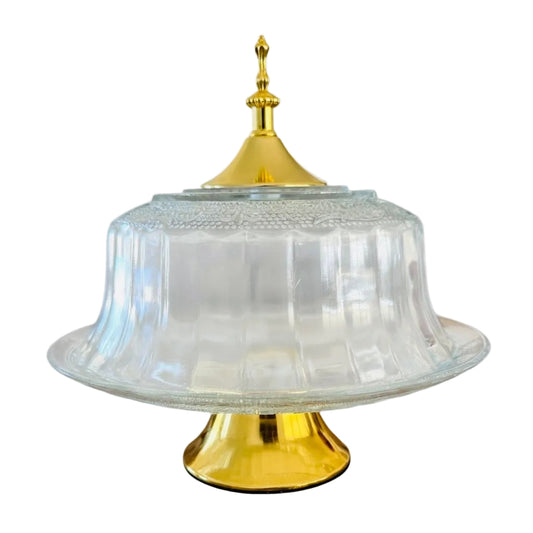 Clear glass cake plate with dome cover and gold details on a white background
